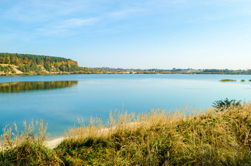 autumn landscape with lake, forest and falling leaves
