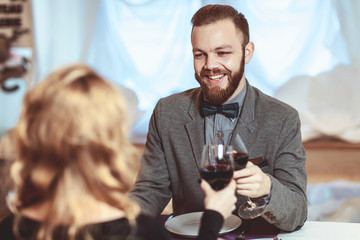 Beautiful young couple with glasses of red wine in luxury restaurant