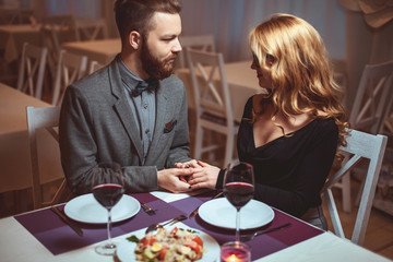 Beautiful young couple with glasses of red wine in luxury restaurant
