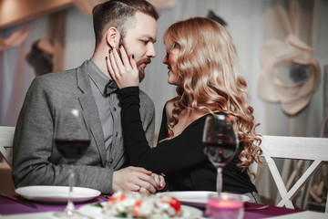 Beautiful young couple with glasses of red wine in luxury restaurant