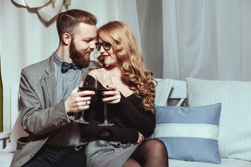 Beautiful young couple with glasses of red wine in luxury restaurant