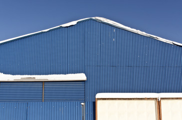 Fototapeta premium Snow on the roof of blue metal warehouse.
