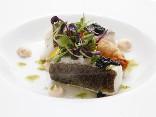 Close up of baked sea bass with vegetables on a dish
