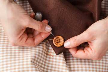 Woman Hands sewing button on fabric - 100889753