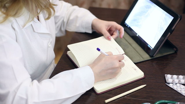 Doctor working with tablet computer and documents
