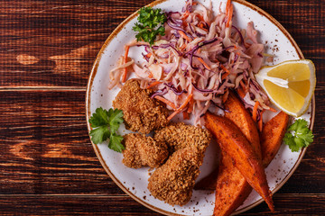 Homemade cooked сhicken nuggets, sweet potatoes and coleslaw.