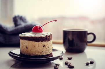 Sweet cake with a cherry and cup of coffee