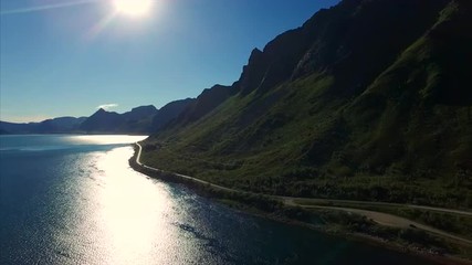 Scenic coastal road on Lofoten islands in Norway, aerial view against sun. Aerial 4k Ultra HD.