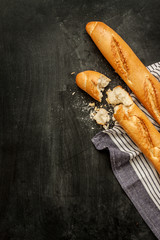 Two french baguettes on black chalkboard background captured from above (top view). Poster layout with free text space.
