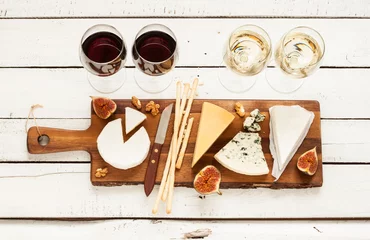  Red and white wine plus different kinds of cheeses (cheeseboard) on rustic wooden table. French food tasting party or feast scenery from above (top view). © pinkyone