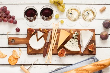 Schilderijen op glas Red and white wine plus different kinds of cheeses (cheeseboard) on rustic wooden table. French food tasting party or feast scenery from above (top view). © pinkyone