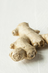 Fresh ginger root on white rustic wooden table - close up. Aromatic and spicy food ingredient -...