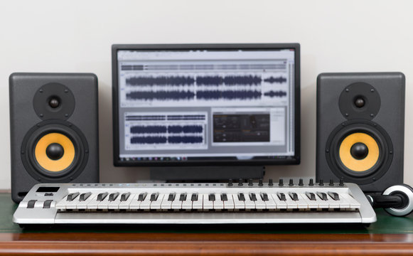 Home recording studio with professional monitors and midi keyboard.