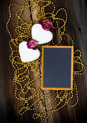 Two White Heart Shaped Cookies, Blackboard, Golden Beads And Dried Roses On Very Old Wooden Board. Happy Valentines Day. Romantic Composition.