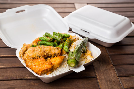 Convenient but unhealthy polystyrene lunch boxes with take away meal on wooden table