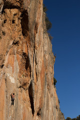 Young male climber hanging by a cliff.