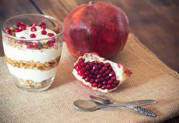 Healthy Breakfast - yogurt with homemade granola and pomegranate on the bright wooden board