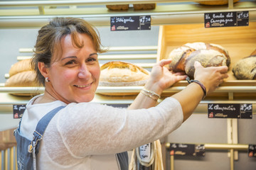 smiling woman with an apron selling bread in a bakery