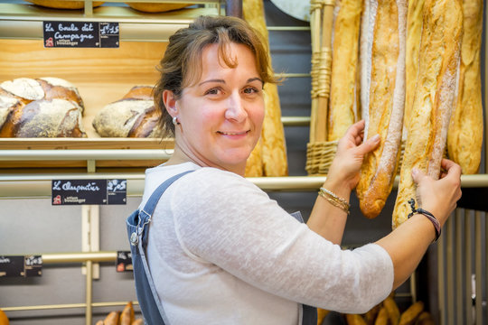 smiling woman with an apron selling bread in a bakery