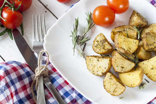 Delicious baked potato with rosemary in white plate on table close up