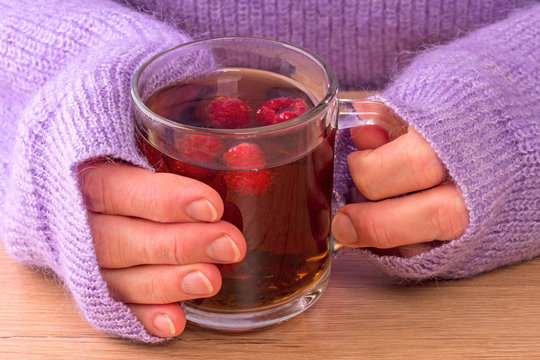 Woman and a glass of hot tea with raspberries