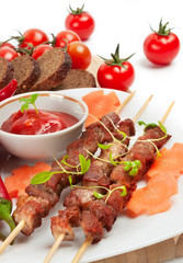 Shish kebab with herbs on a white plate