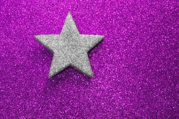 Fototapeta na wymiar lone silver star silver on glitter material on purple background