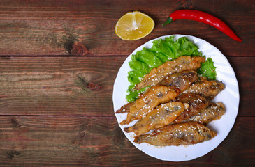 closeup of a plate with spanish boquerones fritos, battered and fried anchovies typical in Spain, on a rustic wooden table