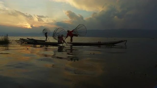Traditionally dressed fishermen from Intha ethnic group of Shan state are posing for tourist on bamboo boats on Inle Lake in Myanmar.