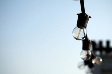 Light bulbs hanging on a electricity wire in clear blue sky background