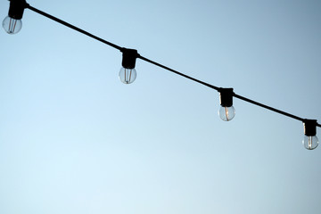 Light bulbs hanging on a electricity wire in clear blue sky background