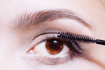 Obraz premium Woman applying mascara on her eyelashes