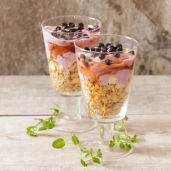 cup of blueberry yogurt with granola and honey