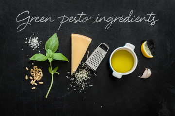 Green basil pesto - italian recipe ingredients on black chalkboard background from above. Parmesan...