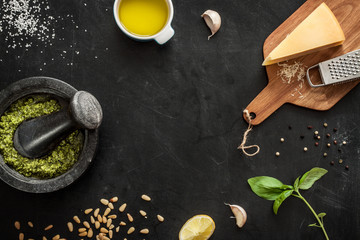 Green basil pesto - italian recipe ingredients on black chalkboard from above. Parmesan cheese,...