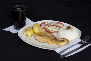 Grilled fish and vegetables, potatoes, rice, tomatoes and chicha morada.