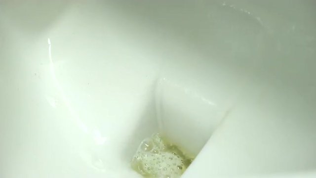 Pee in men's urinal flushed down the drain with water.