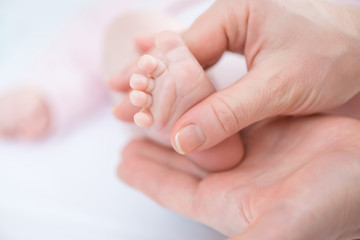 Caring mother holding foot of her infant