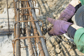 Close up of construction worker hands working with pincers on fi