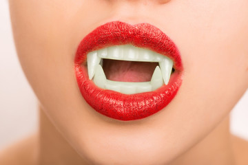 Young girl wearing make up and fake vampire teeth.