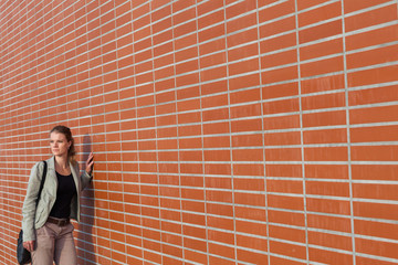 Young beautiful blonde next to a brick wall