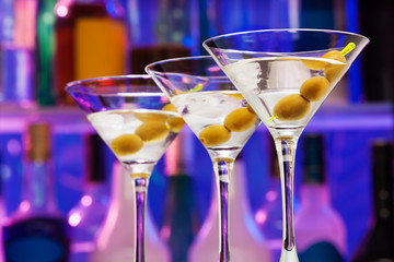 Several cocktail glasses with olives in the bar