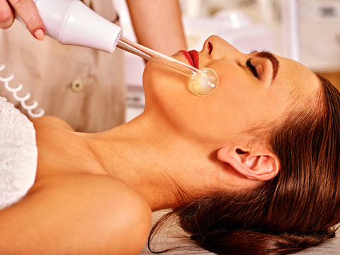 Young woman receiving electric darsonval facial massage procudure after procedure . 