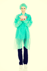 Female doctor with pink piggy bank.
