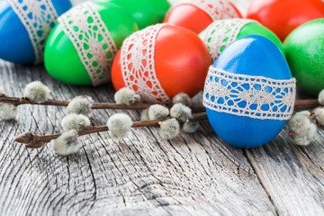  Easter eggs decorated with lace and willow branch on wooden background. Selective focus, copy space