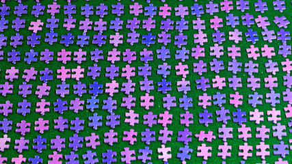 purple puzzle pieces sorted neatly on a green table cloth