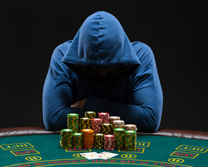 Portrait of a professional poker player sitting at pokers table - obrazy, fototapety, plakaty