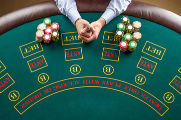 Closeup of poker player with chips at green casino table