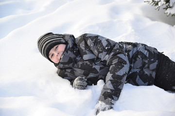Teen boy lies on   snow in the winter forest © olgavolodina