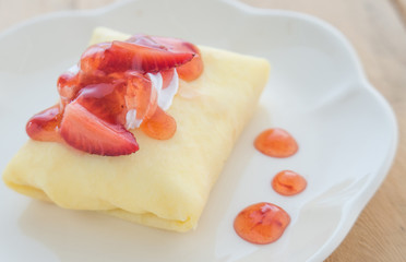 Strawberry crepe cake,White dish,Wooden floor.